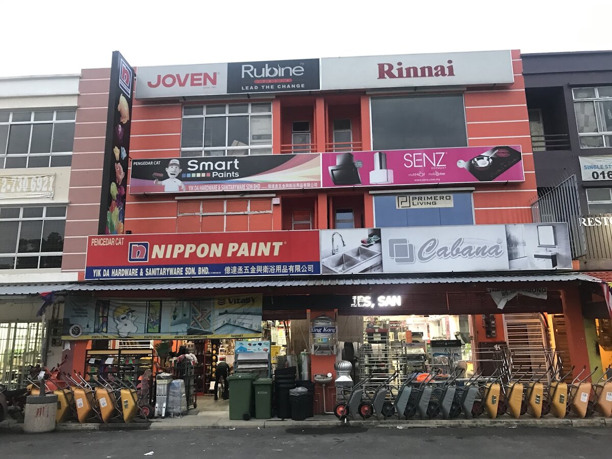 Orange three-storey shophouse with Joven, Rubine, Rinnai, Smart Paints, Senz and Nippon Paint signboards and wheelbarrows lined up at the front