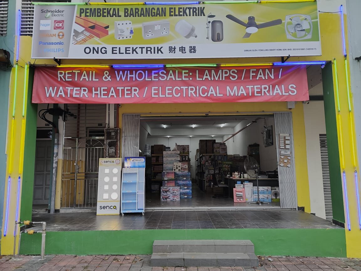 Shopfront with a signboard reading Ong Elektrik 财电器 and Pembekal Barangan Elektrik, a red banner reading Retail and Wholesale: Lamps, Fan, Water Heater, Electrical Materials, and stocked shelves inside