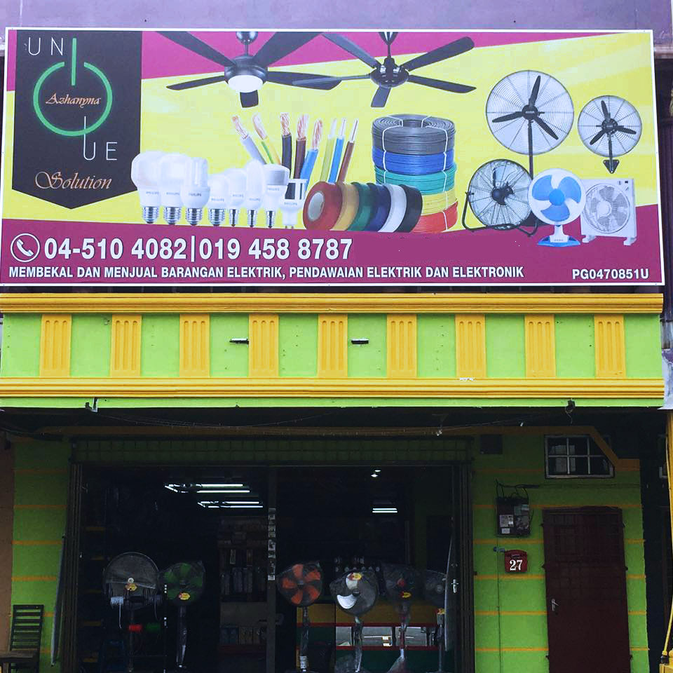 Shophouse with a pink and yellow signboard showing fans, cable coils and LED bulbs, two phone numbers, and stand fans visible through the glass front