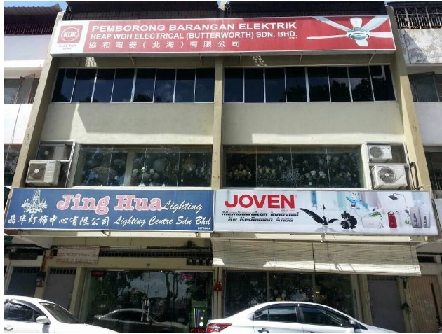 Three-storey shophouse with a red Heap Woh Electrical sign on top and blue Jing Hua Lighting and white Joven signs over the ground floor