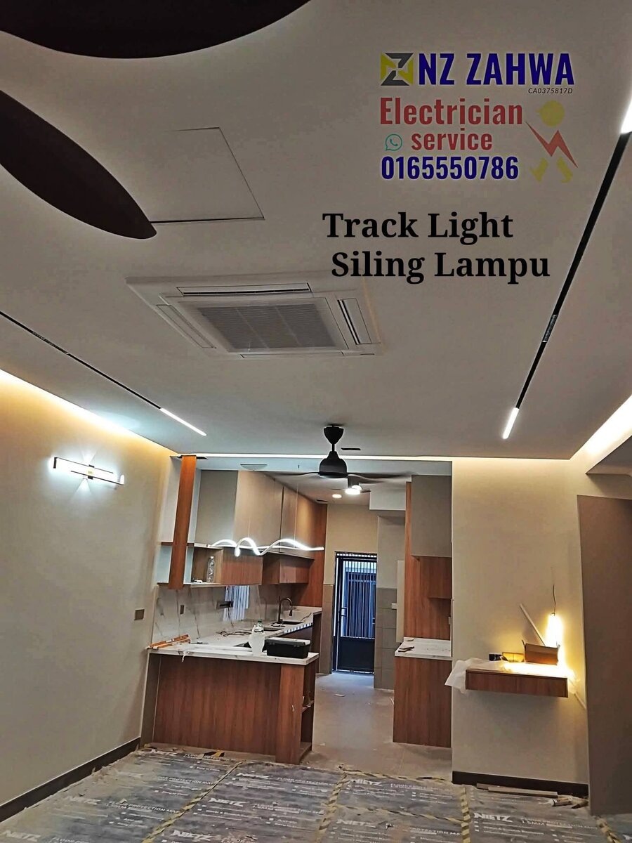 Living and kitchen area with plaster ceiling, black linear track lights, a cassette air conditioner and a ceiling fan, with protective sheets on the floor and an NZ Zahwa watermark