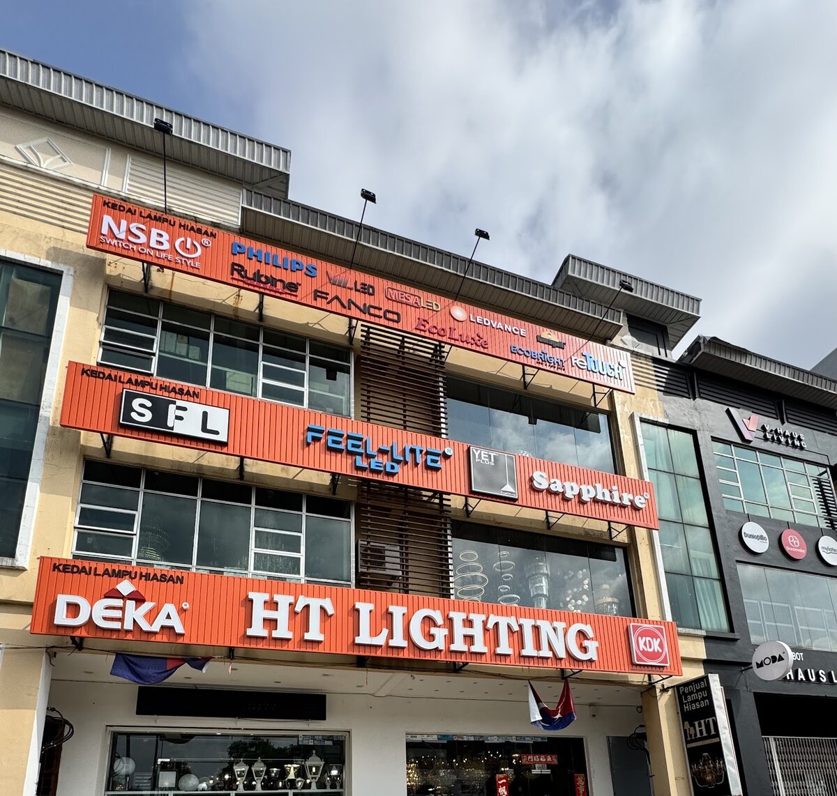 Four-storey shop with orange signboards for HT Lighting and many lighting and fan brands