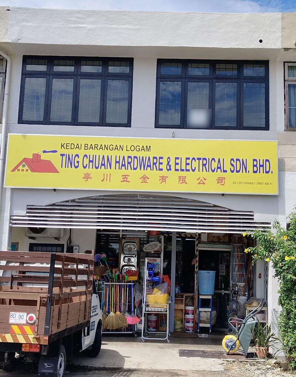Two-storey shophouse with a yellow Ting Chuan Hardware & Electrical signboard, brooms and household goods at the open front and a lorry parked on the left