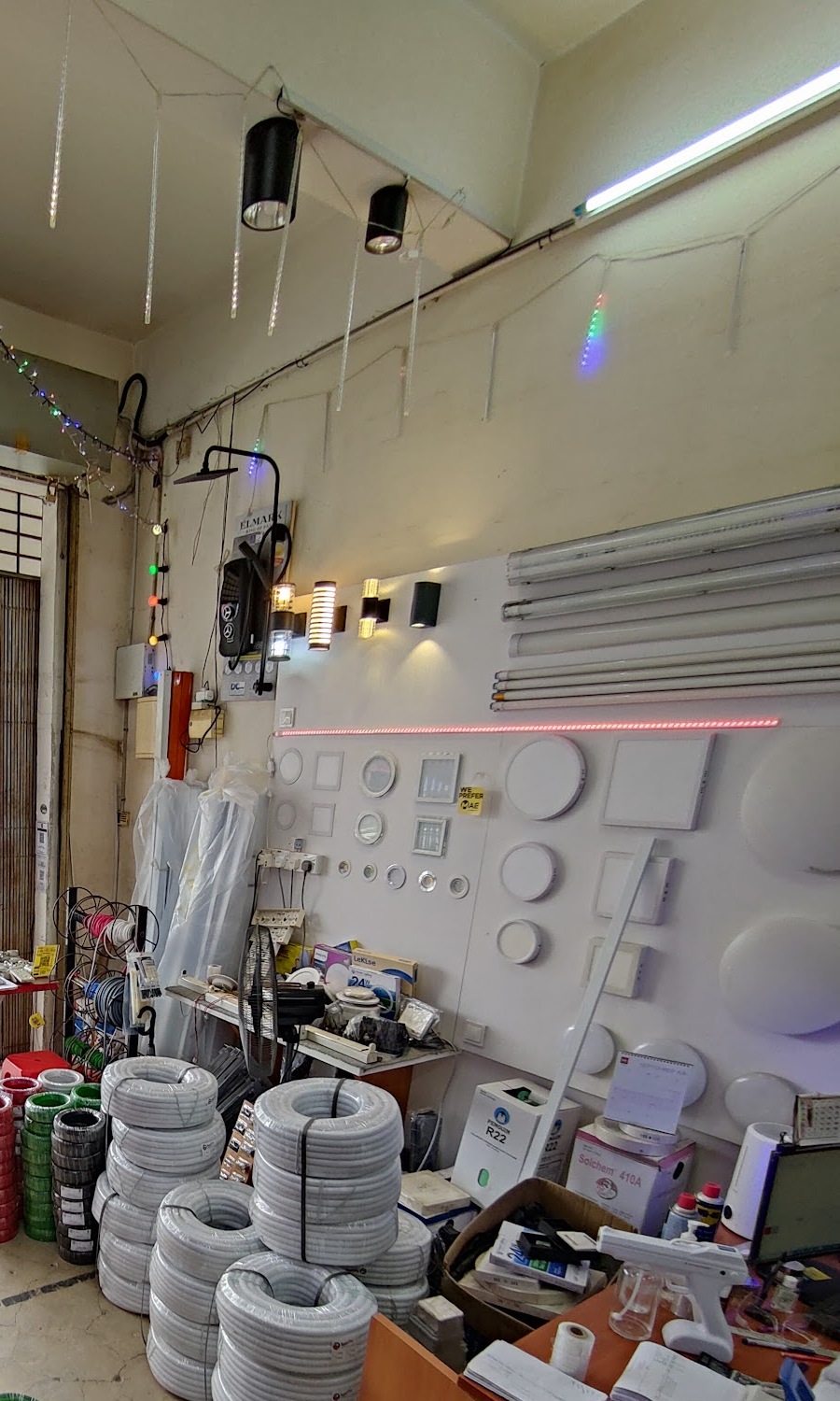 Shop interior with stacked white conduit coils, a sales desk and ceiling and wall lights on display