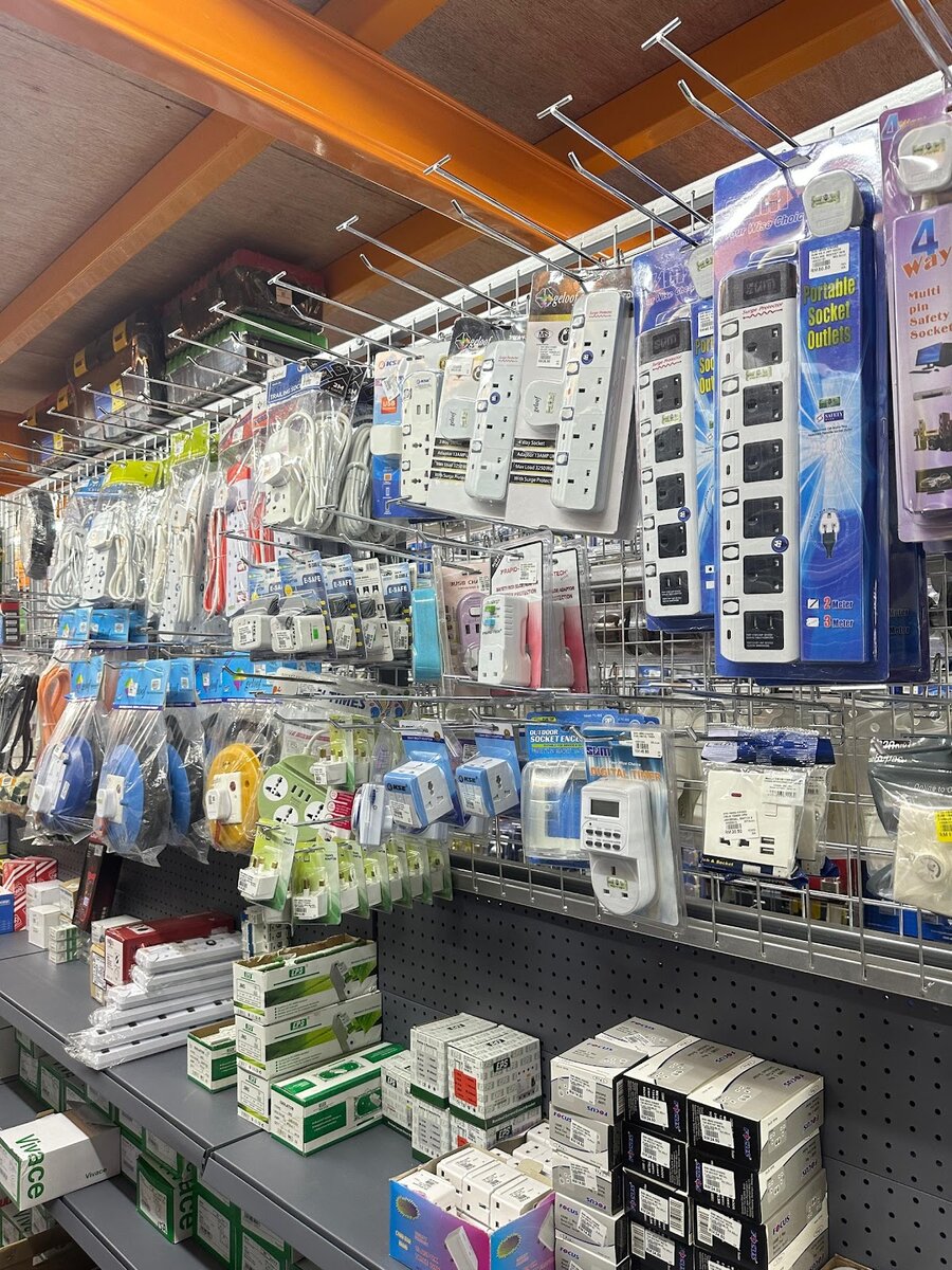 Wire display of packaged extension sockets, cable reels, plug adaptors and a digital timer, with boxed switch sockets, circuit breakers and isolators on the shelves below