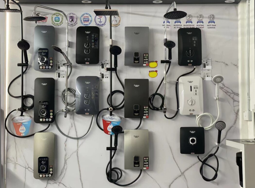 White marble-effect display wall with about a dozen Rubine instant water heaters in black, silver and white, each with a hand shower