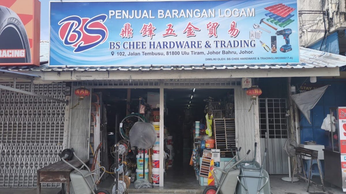 Shopfront with a blue BS Chee Hardware & Trading signboard, paint tins, hose reels and wheelbarrows at the entrance