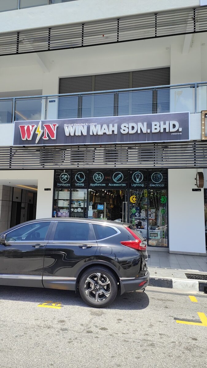 Street-level shop front with a WIN MAH SDN. BHD. signboard in a modern commercial block, a car parked in front
