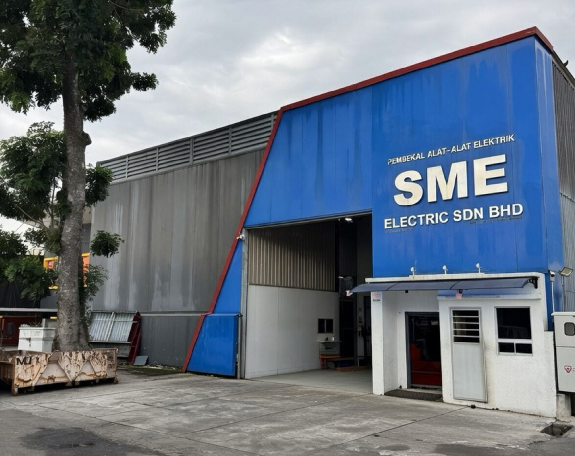 Industrial building with a blue and grey cladded front, a large loading entrance and the sign Pembekal Alat-Alat Elektrik SME Electric Sdn Bhd