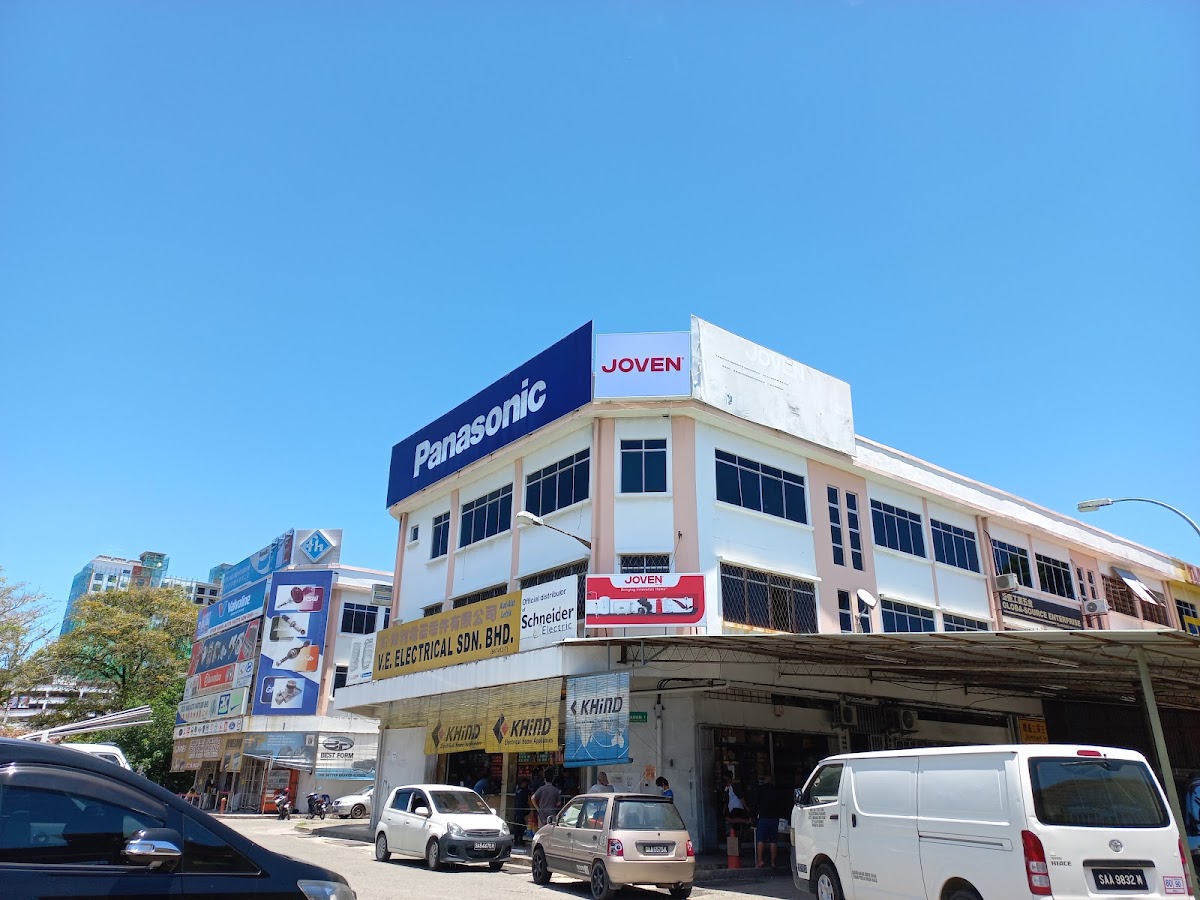Three-storey corner shophouse with a yellow V.E. Electrical signboard, a Schneider Electric sign and a large Panasonic sign on the roofline