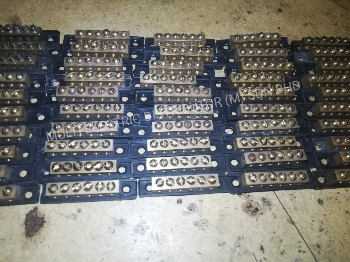 Rows of brass terminal bars with screw terminals mounted on black insulating bases, laid out on a floor
