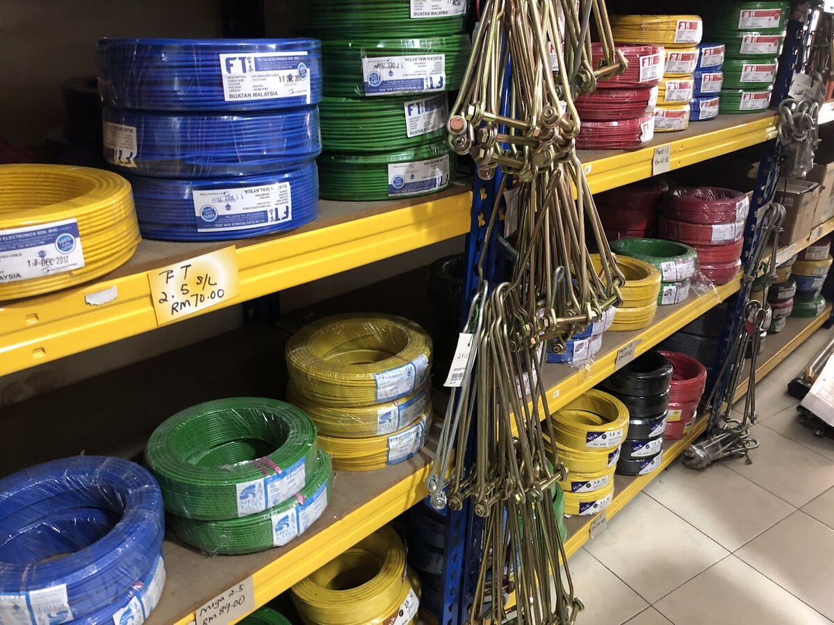 Yellow shelves of blue, green, yellow and red cable coils with handwritten price cards and hanging steel hooks
