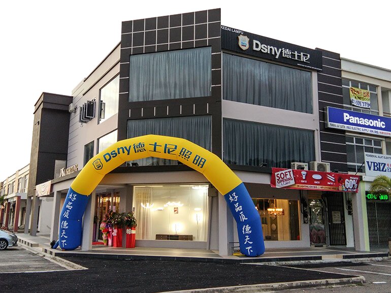 Corner shop with a Dsny 德士尼 sign, an inflatable yellow and blue arch and a bright lighting showroom behind glass