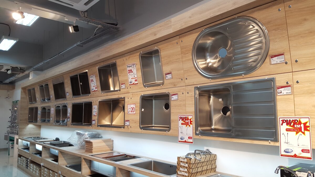 Showroom wall of stainless-steel kitchen sinks set into wood-effect counters with price tags