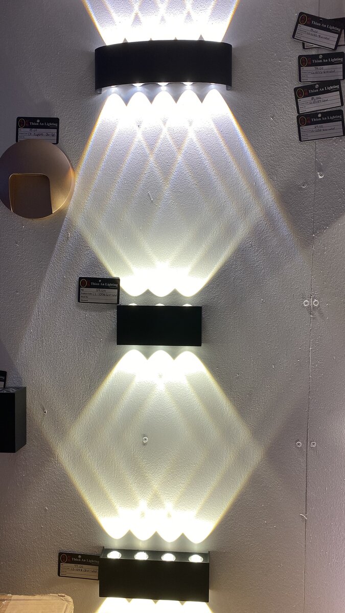 Black rectangular wall lights casting fans of white light up and down a display wall