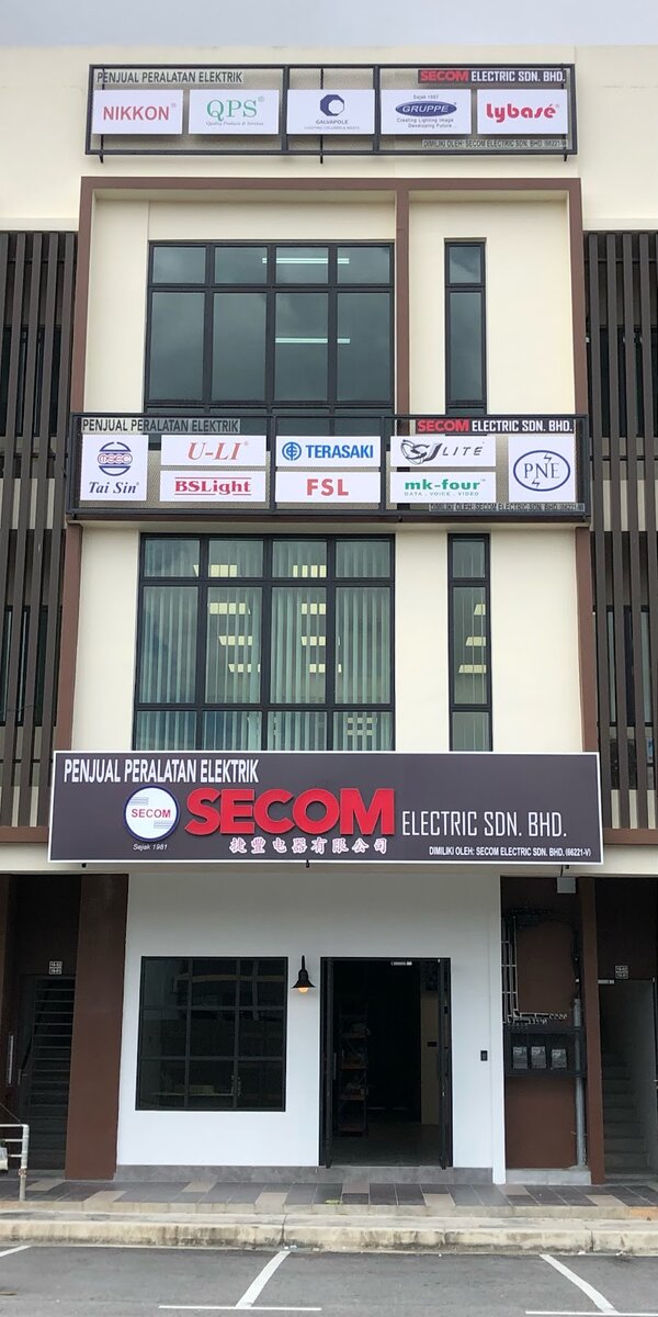 Three-storey shophouse with a dark Secom Electric Sdn. Bhd. signboard over the ground floor and two rows of brand panels including Tai Sin, Terasaki, FSL, SJ Lite and Nikkon on the upper floors