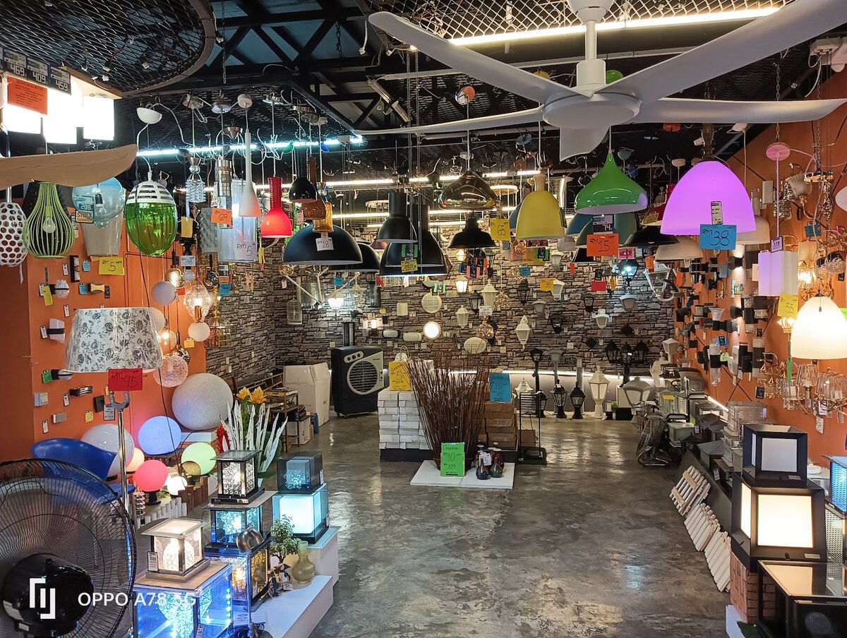 Showroom with dozens of coloured pendant lamps hanging from the ceiling, wall lights on orange and stone-effect walls, cube garden lamps and a white ceiling fan