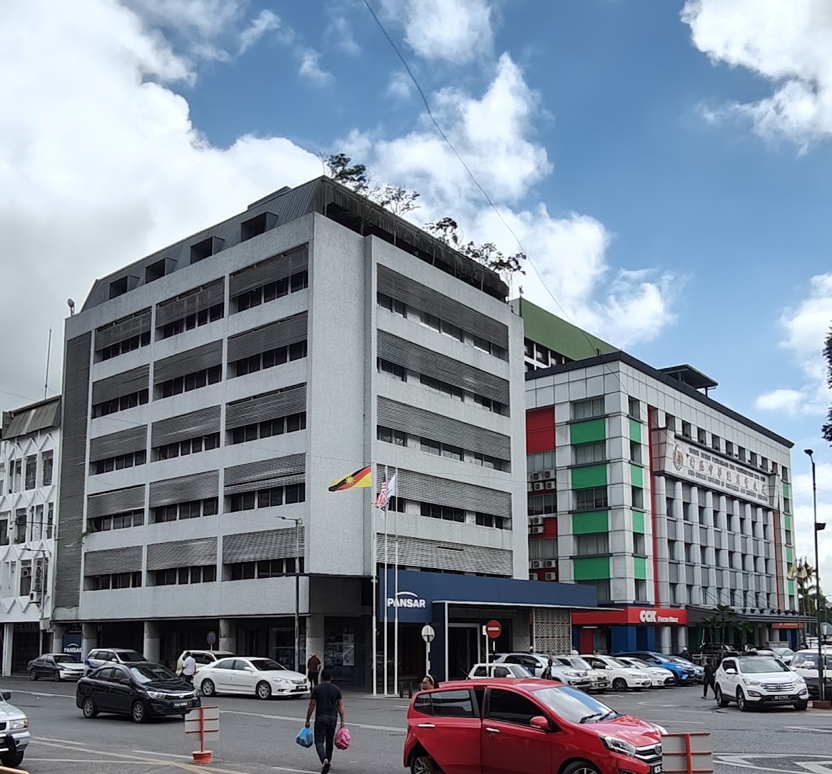 Grey granite-faced office block of about eight storeys with a blue PANSAR canopy over the ground floor, cars parked in front