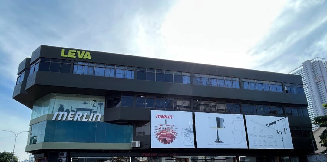 Multi-storey dark building with a large Merlin sign on a glass corner and three lamp posters along the facade