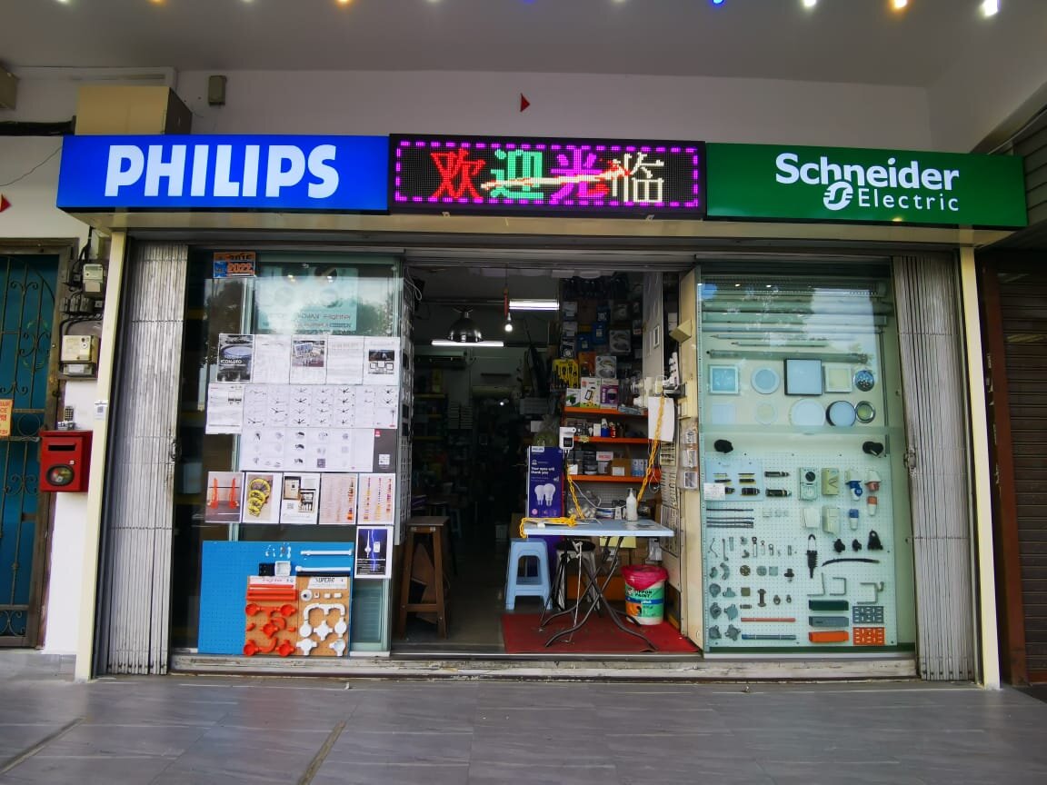 Shop front with Philips and Schneider Electric signs, a window board of electrical accessories and an open doorway into a stocked shop
