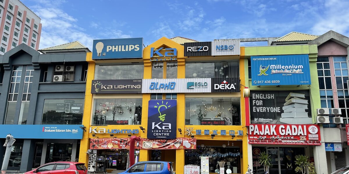 Yellow two-unit shophouse front with Ka Lighting signs and brand signboards for Philips, Rezo, NSB, Alpha, Eglo and Deka, lamps visible in the windows