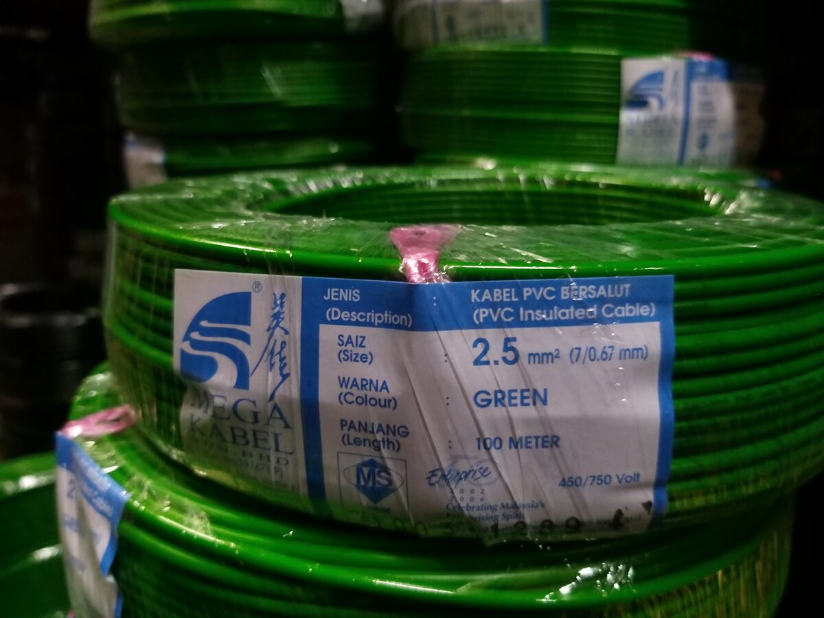 Stacked coils of green insulated cable with a Mega Kabel label giving size 2.5 mm², colour green, length 100 metres, 450/750 volt