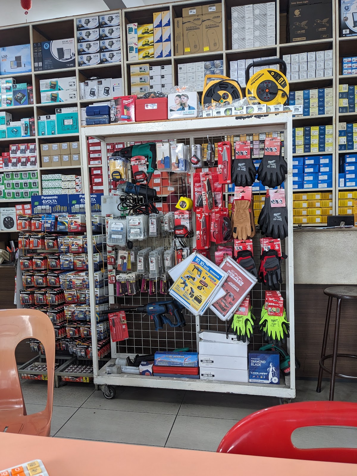Electrical shop interior with floor-to-ceiling shelves of boxed parts and a tool display rack