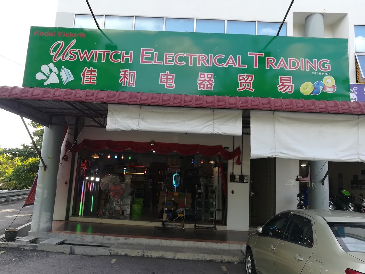 Shop with a green Kedai Elektrik Uswitch Electrical Trading signboard with Chinese characters and lit display inside