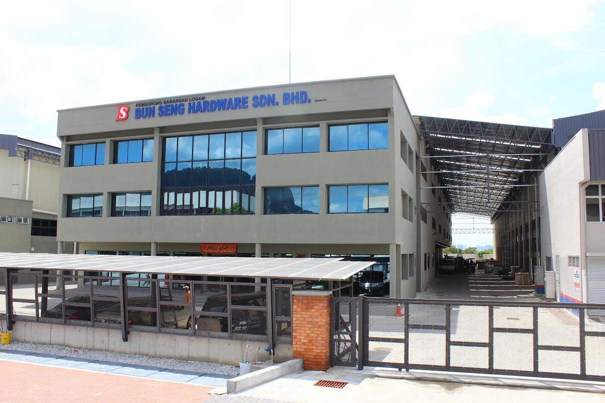 Grey office block with two glazed upper floors, a "Bun Seng Hardware Sdn. Bhd." sign on the roofline and a covered loading bay to the right