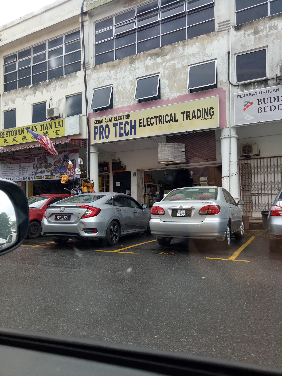 Yellow Pro Tech Electrical Trading signboard on a row of shophouses with cars parked in front