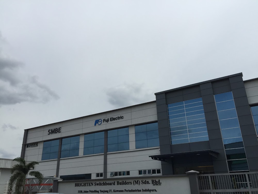Grey factory building with SMBE and Fuji Electric logos behind a gate wall lettered Brighten Switchboard Builders (M) Sdn Bhd