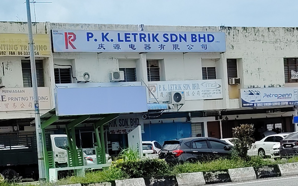 Row of two-storey shophouses with a blue and white signboard reading P.K. Letrik Sdn Bhd and Chinese characters, seen across a road