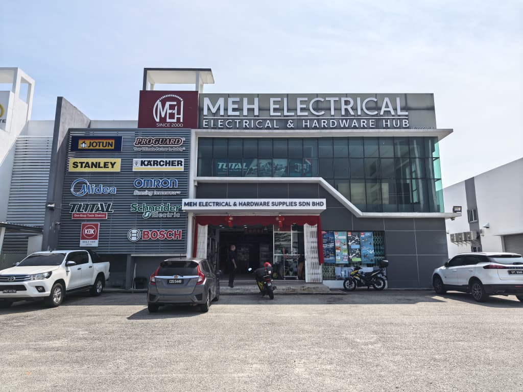 Two-storey commercial building with an MEH Electrical signboard and a wall of brand logos beside the entrance