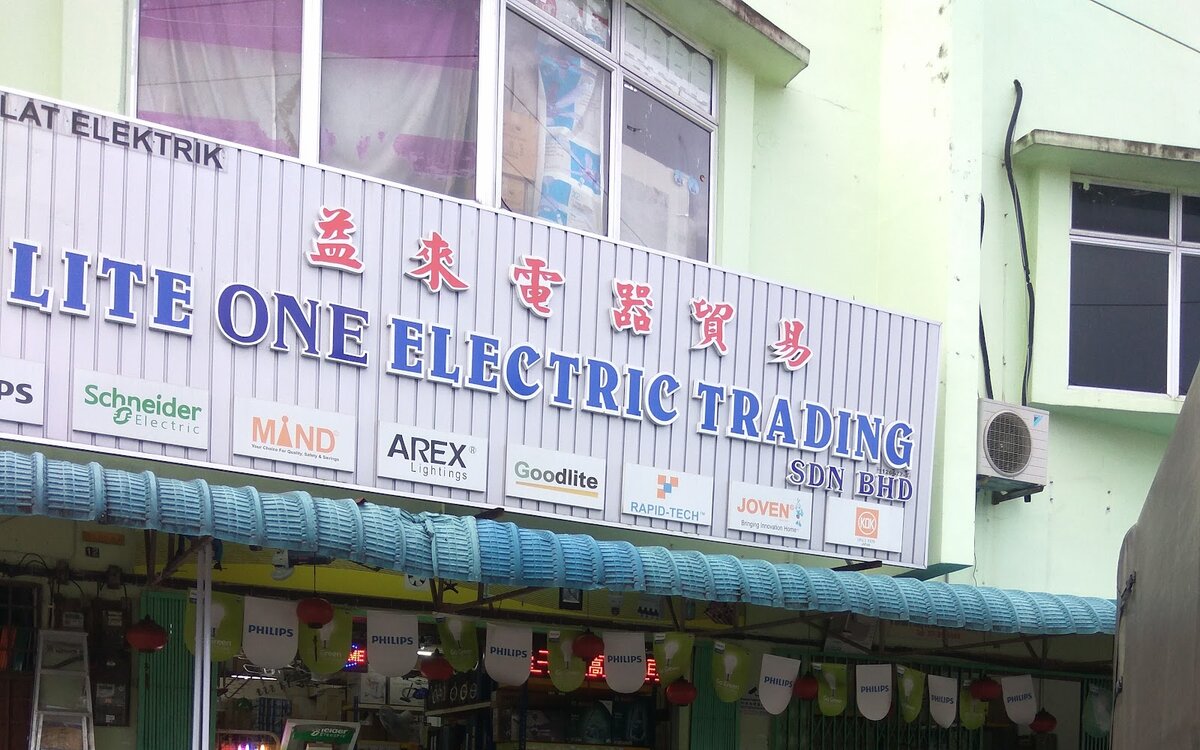 Shop fascia reading E Lite One Electric Trading Sdn Bhd with Chinese characters and a row of brand panels under it