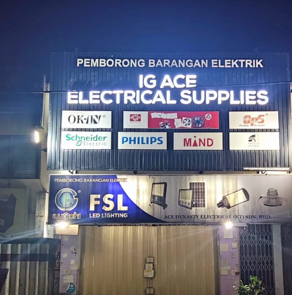 Lit black signboard reading IG Ace Electrical Supplies with brand logos, above a blue FSL LED Lighting panel and a closed shutter