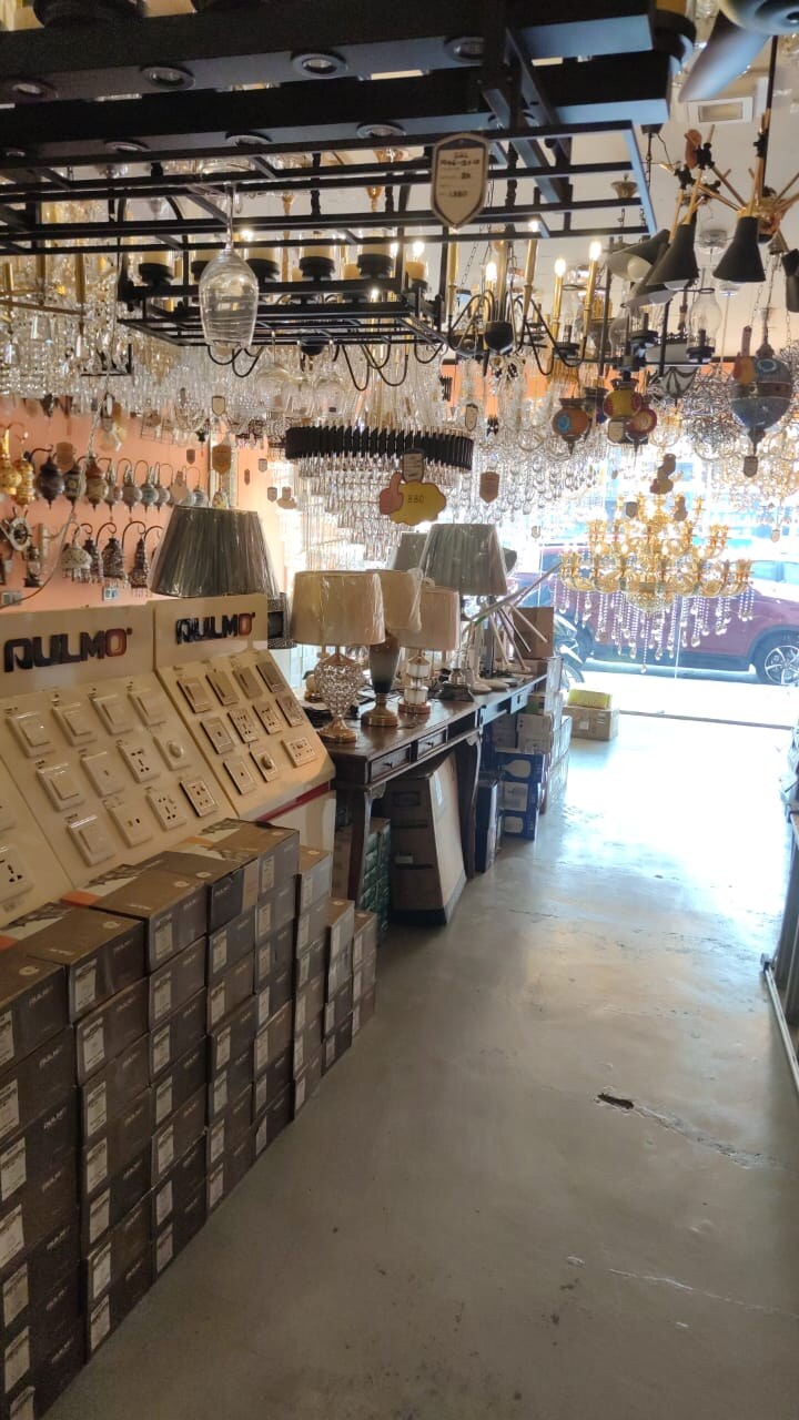 Two white display boards of switches and sockets under Rulmo logos, with dark boxes stacked in front and table lamps behind