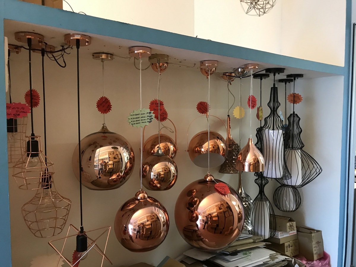 Copper mirrored globe pendant lamps and black wire pendant lamps hanging in a white display niche with red price stars