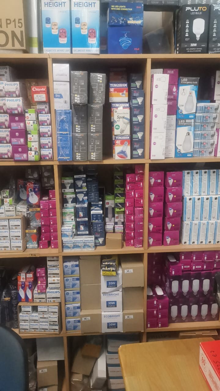 Wooden shelves packed with small boxed light bulbs and lamps in white, pink, blue and black packaging