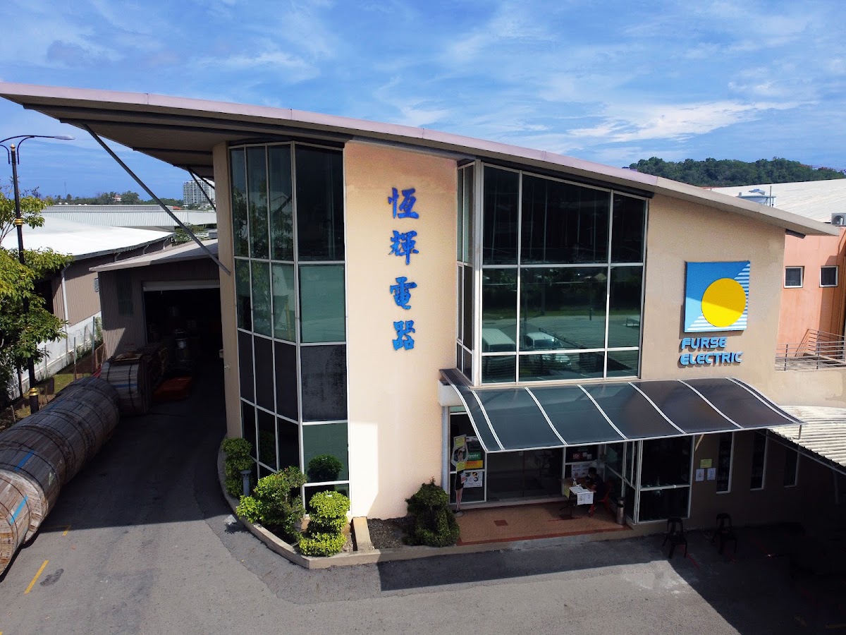 Two-storey glass-fronted building with vertical Chinese characters and a Furse Electric logo, cable drums at left