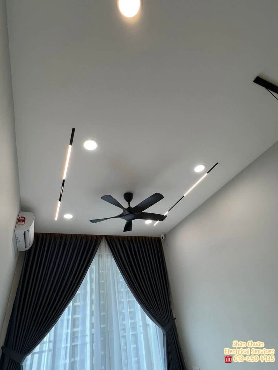 High ceiling with a black five-blade ceiling fan, round downlights and two slim linear lights above tall dark curtains