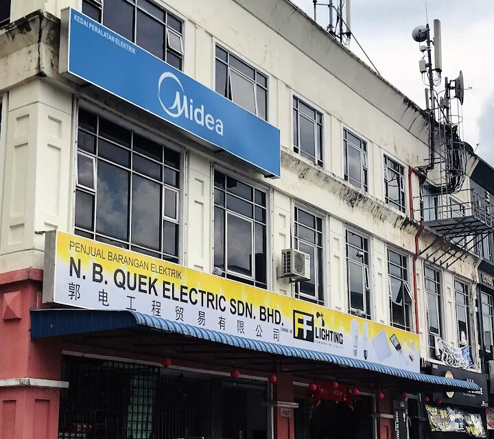 Corner shoplot with a yellow N.B. Quek Electric Sdn. Bhd. signboard and a blue Midea sign above it