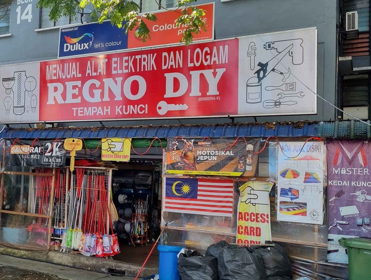Red Regno DIY signboard with a key logo above a shopfront hung with brooms, mops and banners for access-card copying, with a Dulux panel above