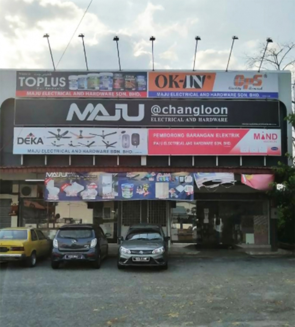 Shophouse front with a black MAJU @changloon signboard, brand panels above and below it and cars parked in front