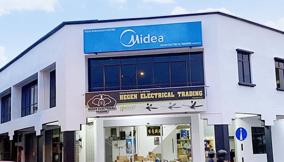 White corner shophouse with a blue Midea sign, a Hegen Electrical Trading signboard with ceiling fans and an open shopfront