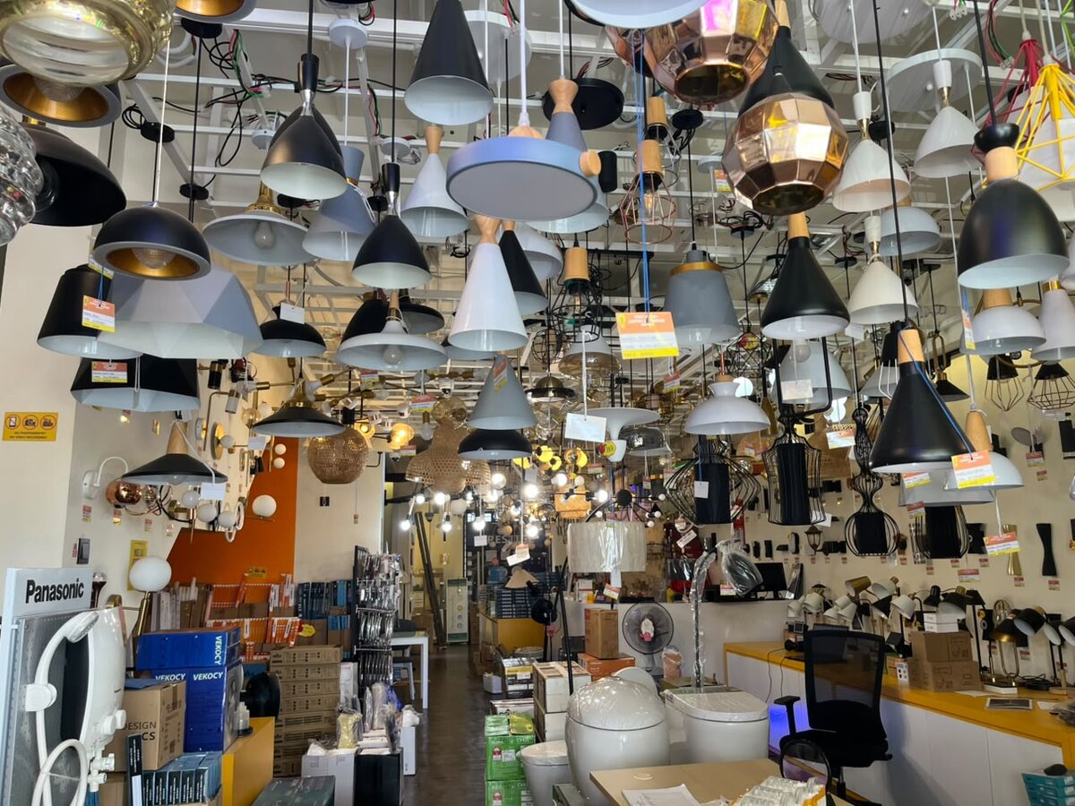 Shop interior with dozens of black, white and copper pendant lights hanging from the ceiling, wall lights and toilet bowls on display