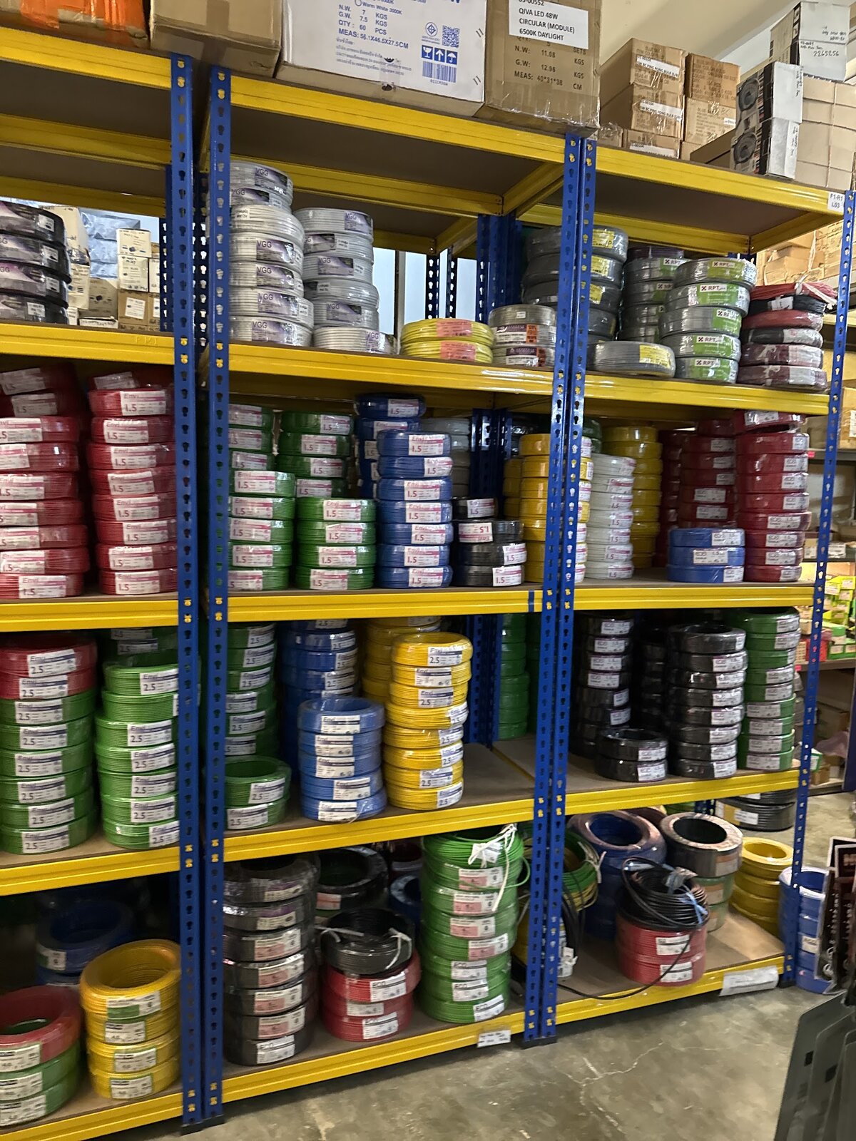 Steel shelving stacked with red, green, blue, yellow and black coils of electrical wire