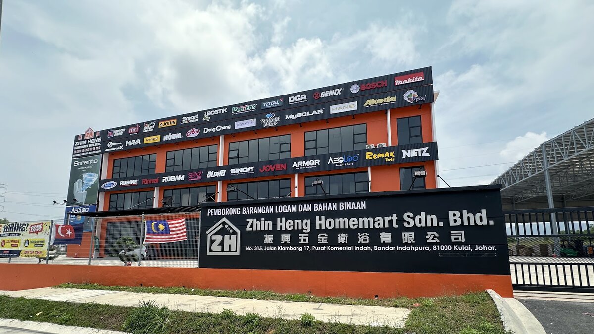 Orange three-storey building covered in paint, tool, water-heater and fan brand logos, with a black signboard reading Zhin Heng Homemart Sdn. Bhd. in front