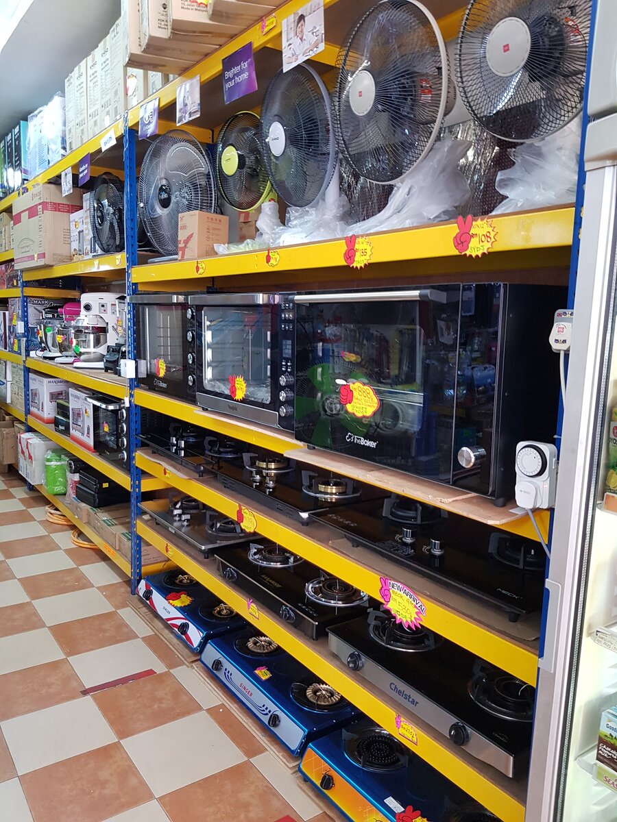 Yellow shelving with wall fans on top, electric ovens in the middle and gas stoves below