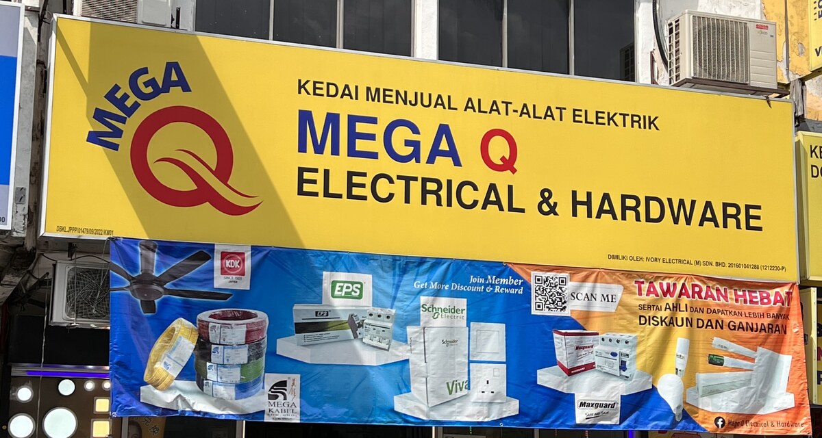 Yellow Mega Q Electrical & Hardware signboard above a blue and orange banner showing a ceiling fan, cable coils, breakers, a Schneider Vivace switch box, a Maxguard RCCB and LED lamps with the words 'Join Member' and 'Tawaran Hebat'