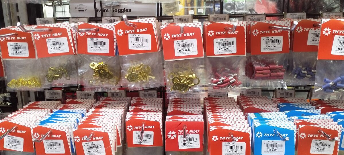 Rows of small packets of brass ring lugs and red and blue insulated crimp terminals, each with a Thye Huat label and price sticker